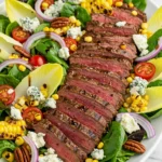 Colorful steak salad with grilled corn, Gorgonzola cheese, cherry tomatoes, and balsamic vinaigrette served on a white platter