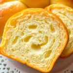 Sliced brioche bread with light golden crust and tender, airy inside displayed on white lace plate