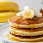 Fluffy Brown Sugar Banana Pancakes stacked on a plate with maple syrup