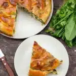 Breakfast quiche slice with sausage, cheese, and herbs on a white plate