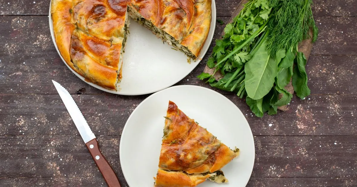 Breakfast quiche slice with sausage, cheese, and herbs on a white plate