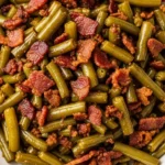 Direct overhead shot of chopped green beans and crumbled crispy bacon with caramelized edges served on a white porcelain plate