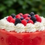 Watermelon cake topped with whipped cream and berries