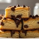 Cake mix cookie bars stacked on a plate with melted chocolate chips