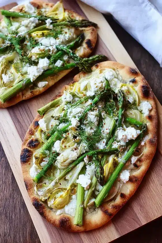 Asparagus goat cheese flatbread cut into portions and served on a wooden board