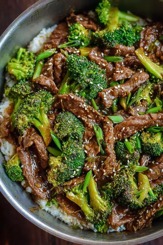 Beef broccoli stir-fry served over white rice in a decorative bowl with chopsticks