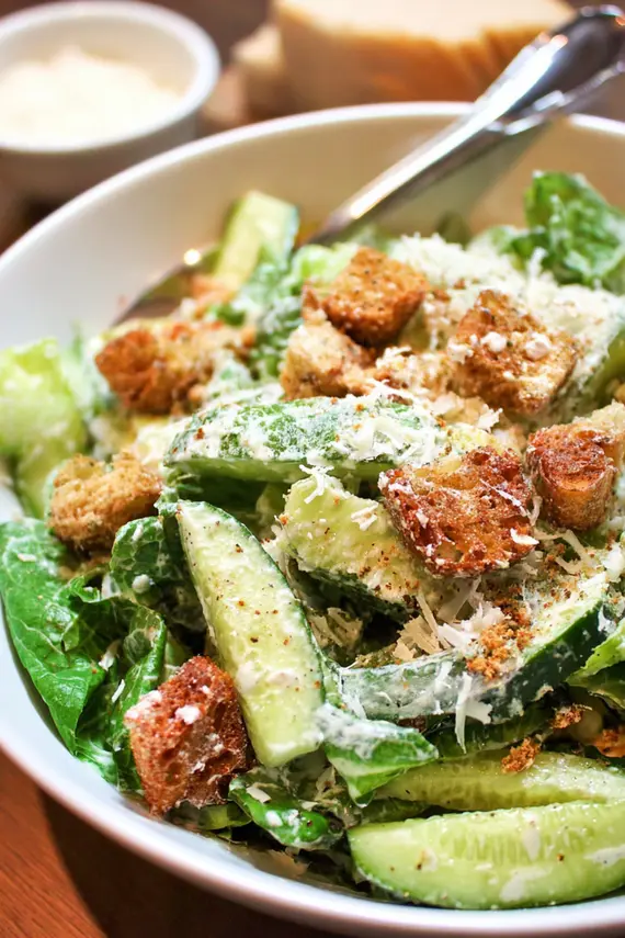 Homemade Caesar dressing in a glass jar with ingredients surrounding it