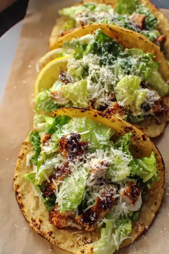 Chicken caesar smash tacos served with a side salad and lime wedges