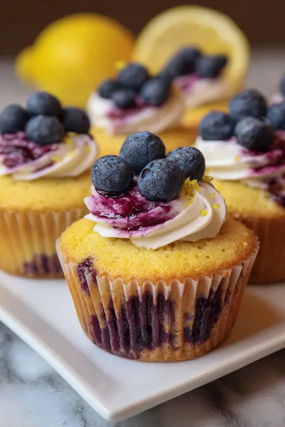 Lemon blueberry cupcakes with translucent citrus glaze dripping down the sides
