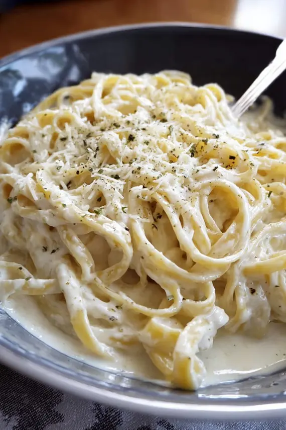 Creamy alfredo sauce being served with garnishes and vegetables