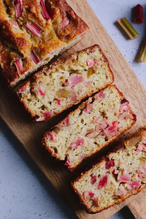 Sliced rhubarb bread on a serving plate with tea and fresh fruit