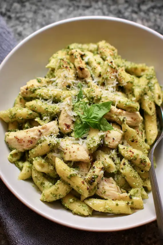 Pesto chicken pasta served on a decorative plate with cherry tomatoes and a sprinkle of Parmesan cheese, ready for serving