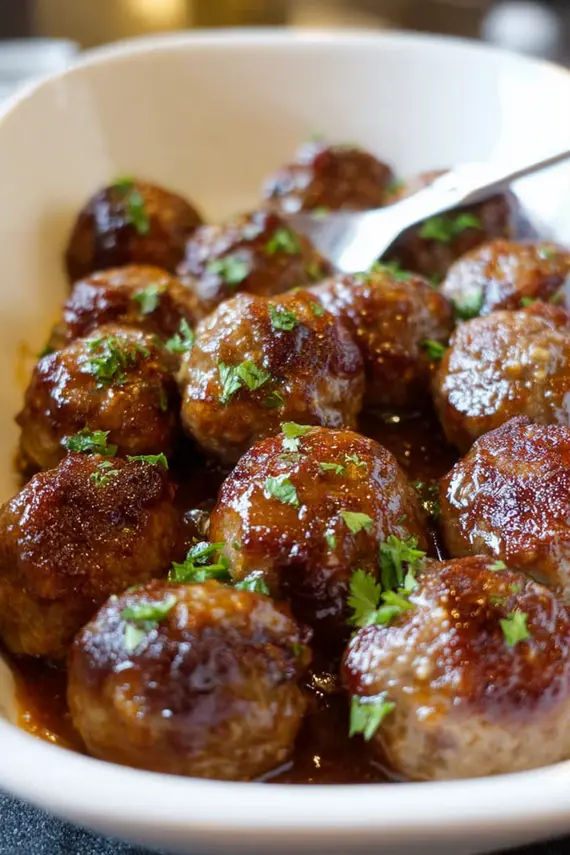 Honey mustard glaze being brushed onto baked meatballs