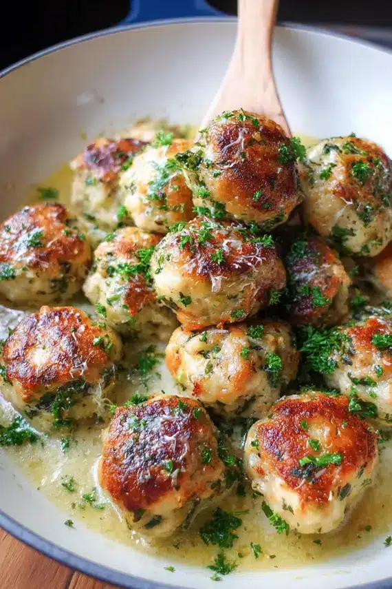 Chicken Piccata Meatballs on a serving platter with lemon slices and fresh herbs