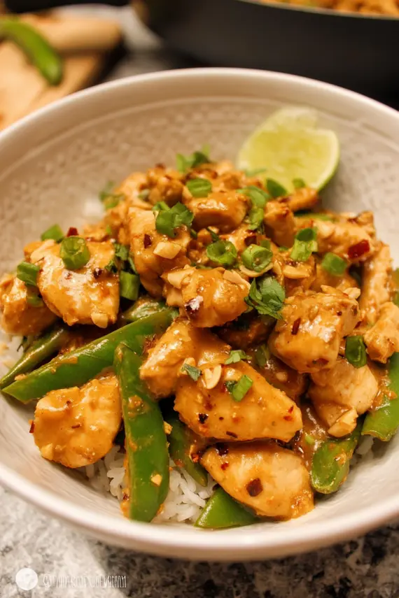 Delicious peanut chicken stir-fry in a wok with colorful vegetables and glossy sauce
