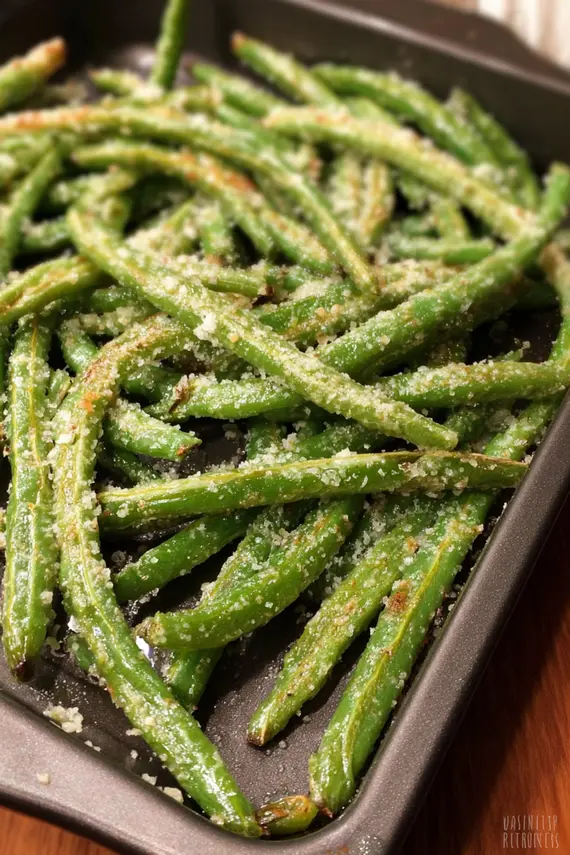 Perfectly roasted green beans with melted Parmesan cheese on a baking sheet