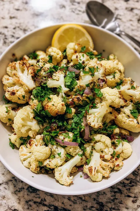 Beautifully plated roasted cauliflower salad with colorful additions like herbs and nuts in an elegant serving dish