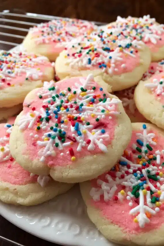 Soft buttery lofthouse style cookies with pink frosting arranged on a serving platter