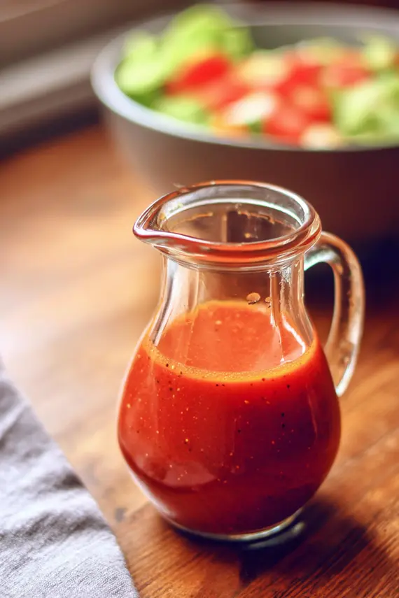 Various ingredients for homemade French dressing arranged on a wooden surface