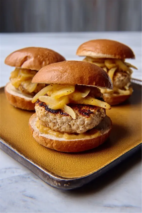 Assembled maple mustard apple chicken burger with lettuce and toppings on a wooden serving board