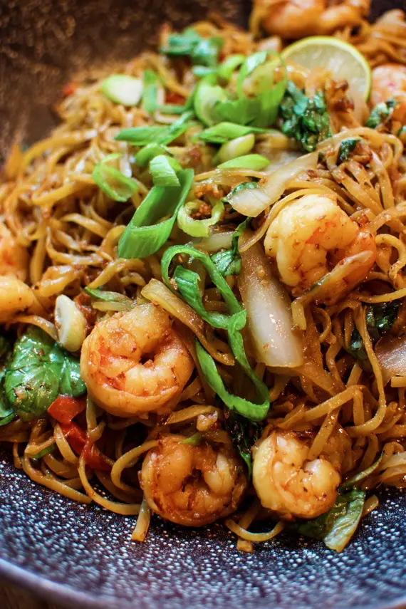 Delicious Asian shrimp noodle stir-fry in a skillet showing pink shrimp, colorful vegetables, and glossy noodles