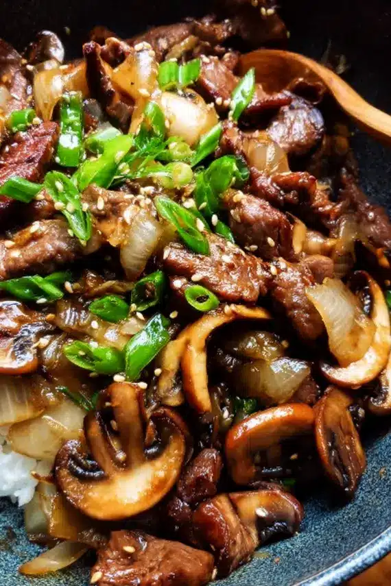 Beef Onion Mushroom Stir Fry in a wok with steam rising