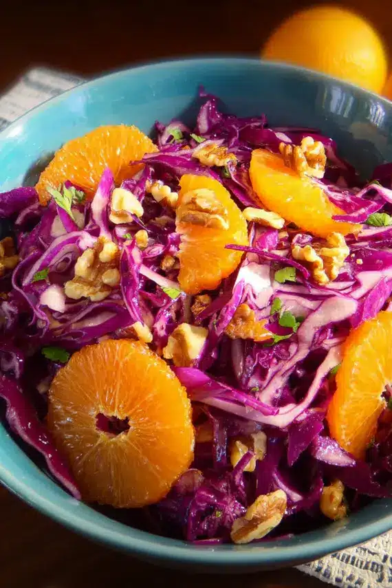Freshly prepared Red Cabbage Clementine Salad in a large bowl showing vibrant purple cabbage, bright orange clementine segments, and toasted walnuts