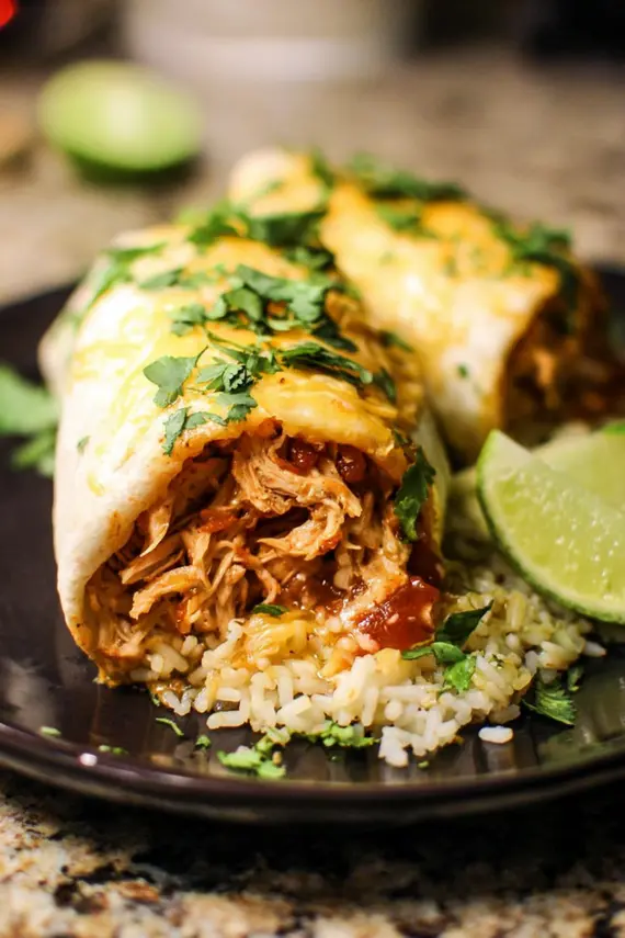 Smothered honey lime chicken burritos arranged on a serving platter with garnishes and side dishes