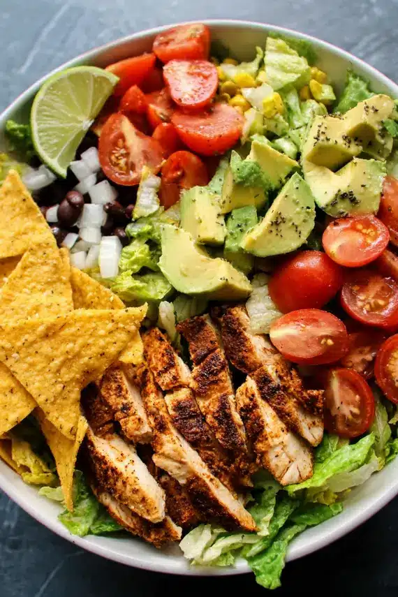 Simple chicken taco salad in a white bowl with crushed tortilla chips on top
