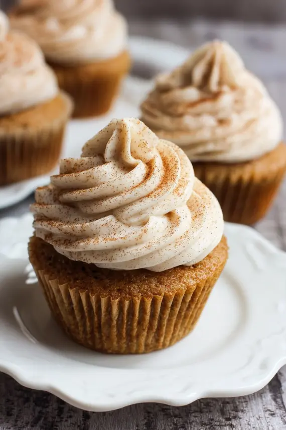 Freshly baked spice cake cupcakes with cinnamon cream cheese frosting on a decorative cake stand