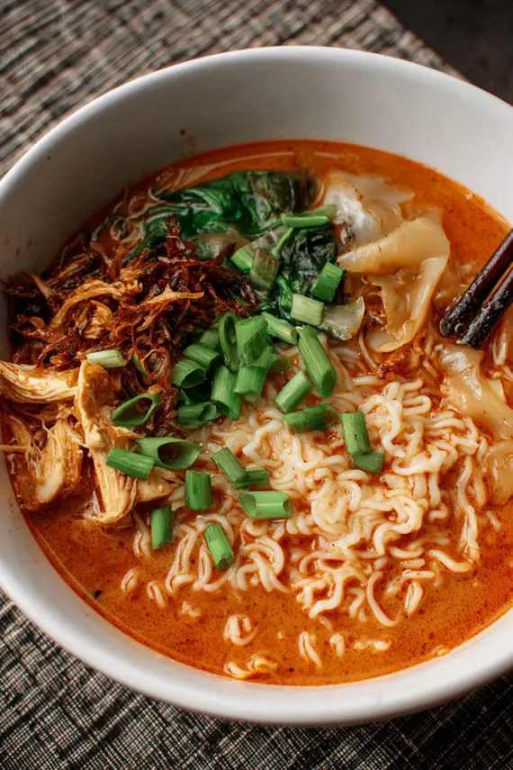 Overhead view of Gochujang Coconut Chicken Noodle Soup with colorful garnishes arranged in serving bowls