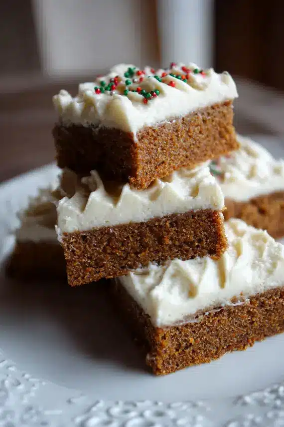 Close-up of cream cheese frosting being spread on gingerbread bars with a spatula