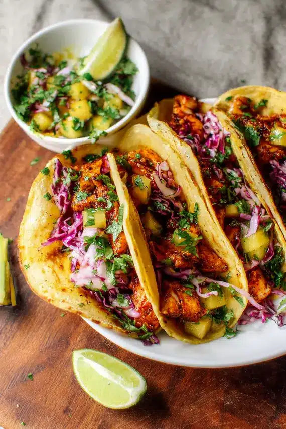 Freshly prepared chili lime fish tacos with colorful toppings and lime wedges
