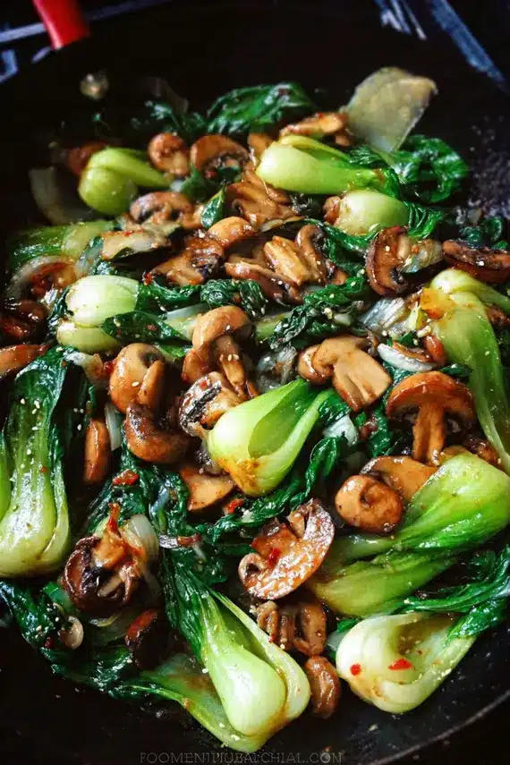 Garlic Mushroom Bok Choy Stir Fry served in a bowl over rice with chopsticks resting beside it