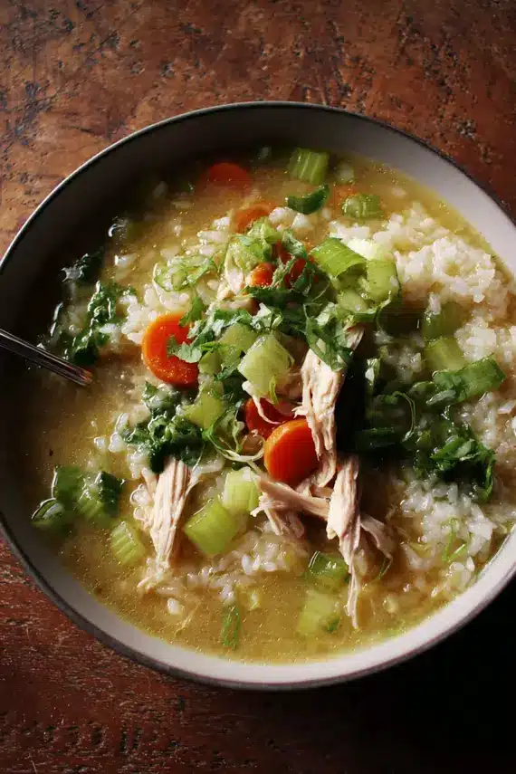 Steaming bowl of ginger chicken rice soup with fresh ingredients