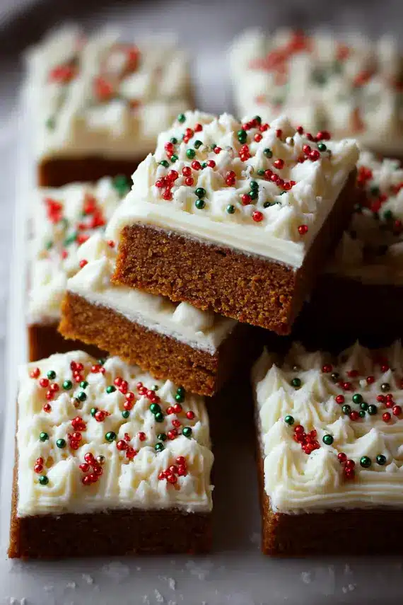 Homemade gingerbread bars with cream cheese frosting cut into squares on a wooden board
