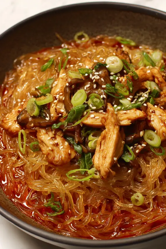 Homemade gochujang sauce being poured over chicken in a skillet