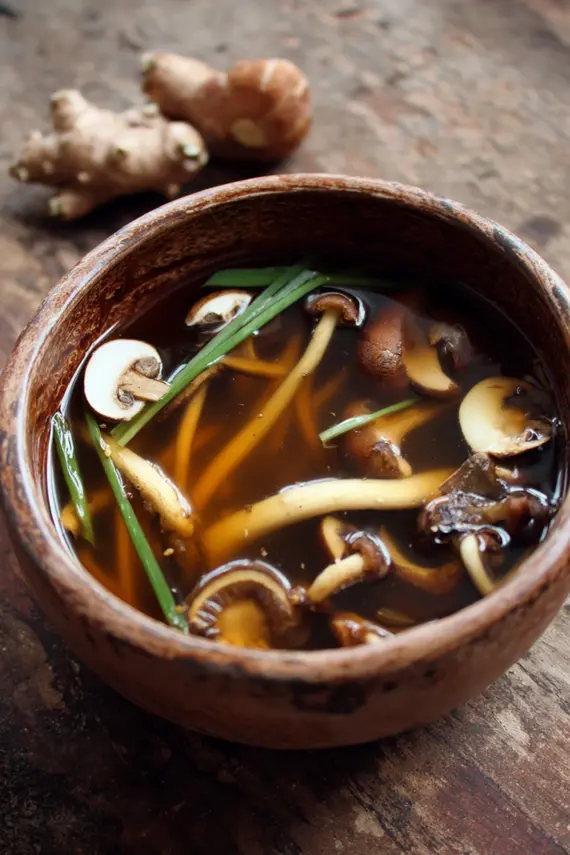 Overhead view of healing mushroom kombu broth in a ceramic bowl with fresh garnishes