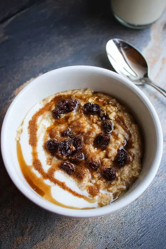 Lightened up cinnamon roll oatmeal topped with yogurt swirl and fresh berries in a ceramic bowl