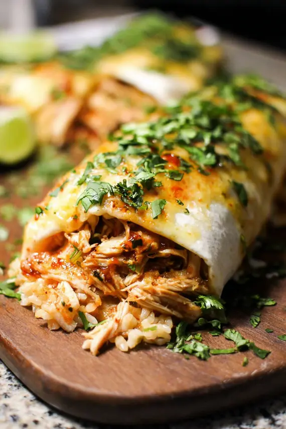 Delicious smothered honey lime chicken burritos on a plate with fresh ingredients surrounding them