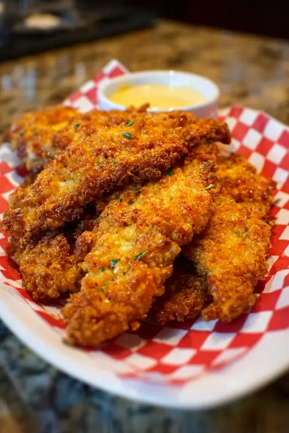 Honey mustard dip in a small bowl next to crispy chicken tenders