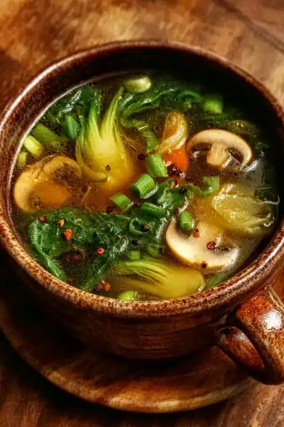 Golden Ginger Garlic Healing Broth in a white bowl with garnishes