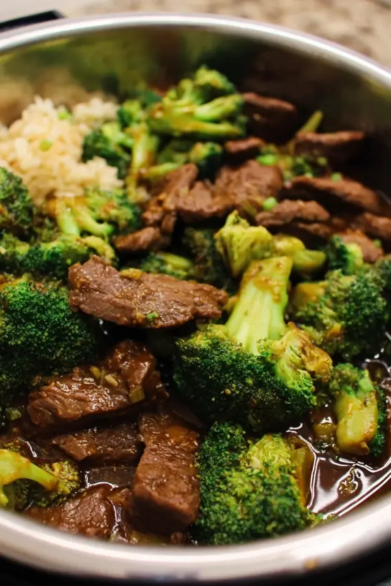 Instant pot beef broccoli served over white rice in a decorative bowl with chopsticks