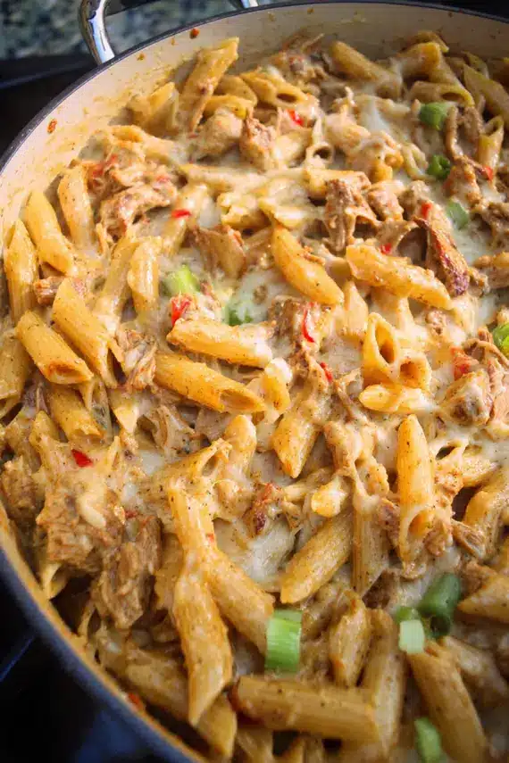 Jerk Chicken Pasta Bake with melted cheese and garnished with green onions