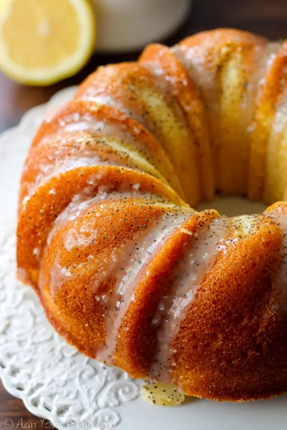 Sliced cinnamon lemon poppy seed bundt cake on a serving plate with fresh berries