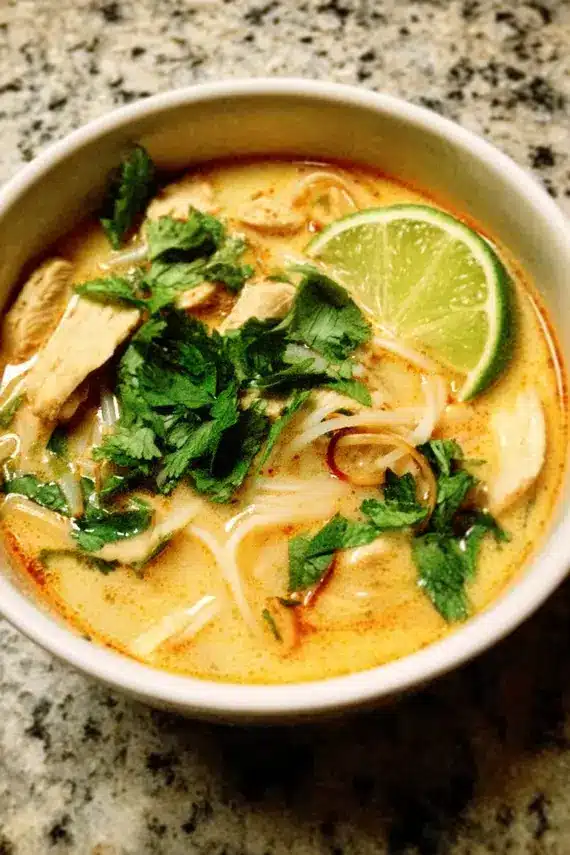 Thai Coconut Chicken Soup garnished with lemongrass and fresh herbs