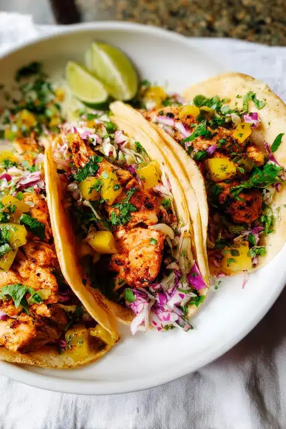 Creamy lime cilantro sauce being drizzled over freshly assembled fish tacos