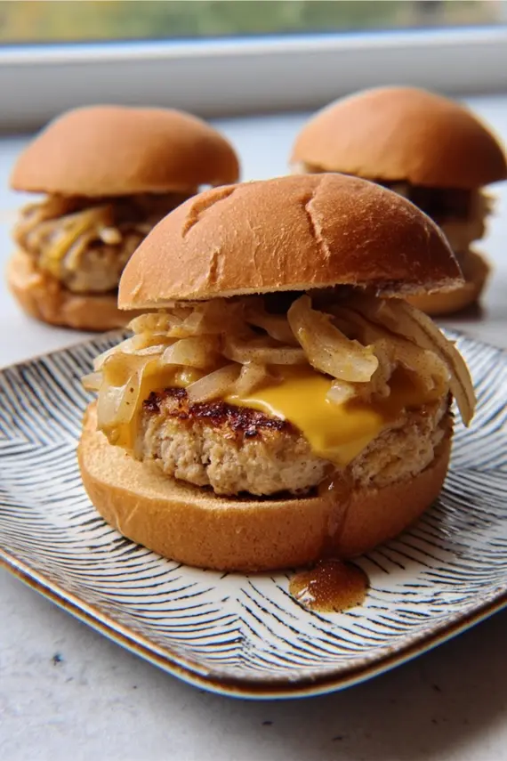 Maple mustard apple chicken burgers cooking on a grill with caramelization forming