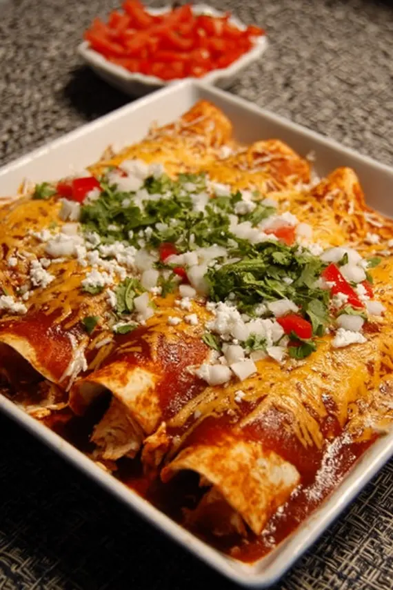 Red Chicken Enchiladas topped with melted cheese and cilantro