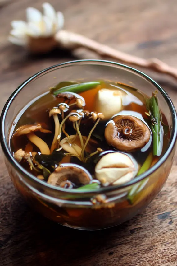 Steaming bowl of healing mushroom kombu broth with shiitake mushrooms and garnishes